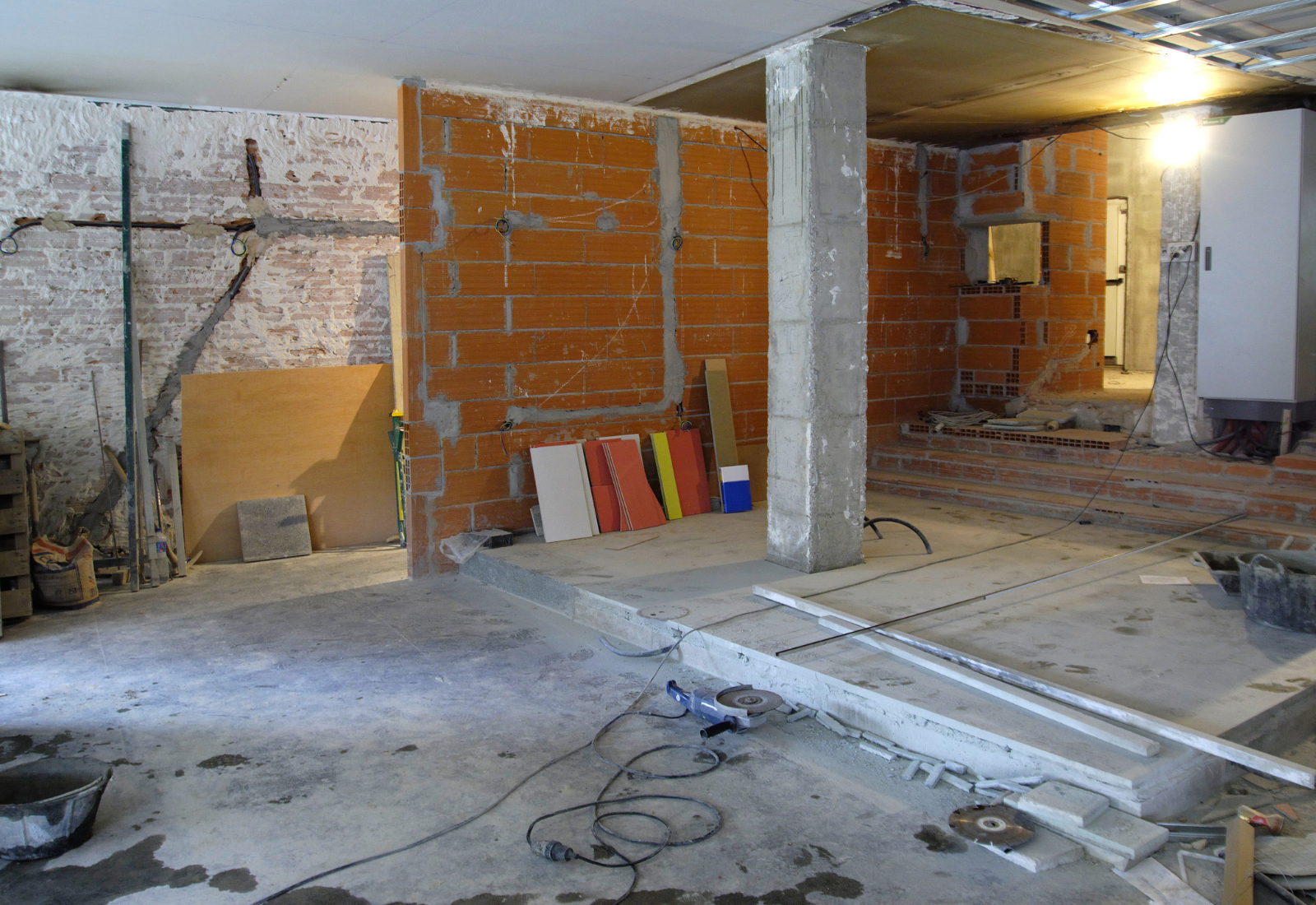 Innenraum während eines Abrisses mit freigelegten Mauern, Baustützen, Bauschutt und sichtbaren Leitungen.