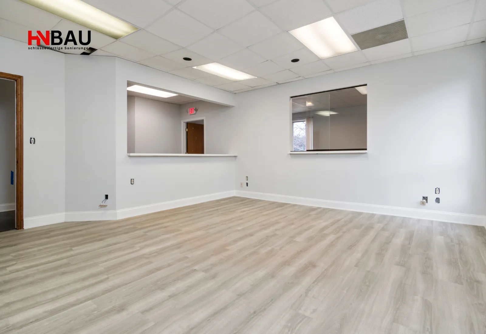 Neu verlegter Laminatboden in einem frisch renovierten Raum mit hellen Wänden und abgehängter Decke; moderner und gepflegter Innenbereich.